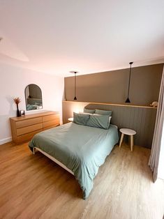 a bed sitting in a bedroom next to a wooden dresser and lamp on top of a hard wood floor