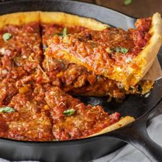 a deep dish pizza in a cast iron skillet with one slice missing from it