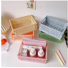 three plastic baskets filled with different items on a white counter top next to pencils and markers