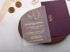 a purple and gold wedding card on top of a wooden plate