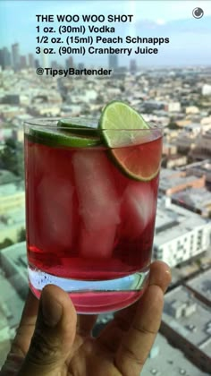 a person holding up a drink in front of a cityscape