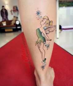 a woman's leg with a tattoo on it that has a little fairy holding a wand