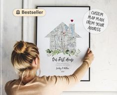 a woman is holding up a poster with a house on it