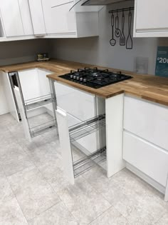 a kitchen with white cabinets and wooden counter tops, an oven and two stools