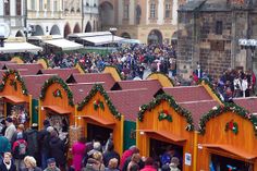 a group of people standing in front of small buildings with christmas decorations on the roof