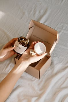 a woman is holding a bottle of wine in her hand while sitting on a bed