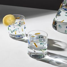 two glasses filled with water sitting on top of a white table next to each other