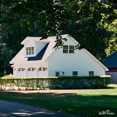 a large white house sitting next to a lush green field with trees in the background