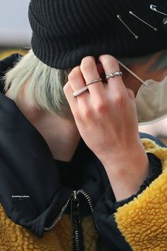 a woman with blonde hair wearing a beanie and holding her hand to her ear