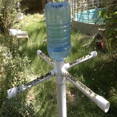 a plastic water bottle on top of a pole in the middle of some grass and bushes