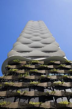 a tall building with lots of plants growing on it's sides, against a blue sky