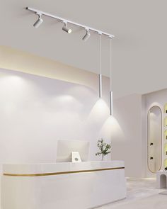 a white reception area with yellow accents on the walls and lights hanging from the ceiling