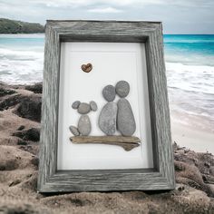 two rocks are placed in a frame on the beach