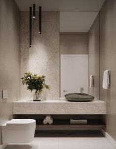 a white toilet sitting next to a bathroom sink under a mirror above a counter top