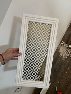 a person holding up a white frame on top of a wooden floor