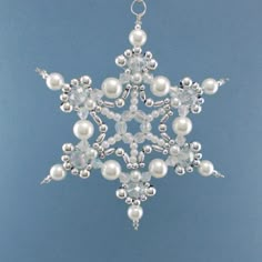 a white snowflake ornament hanging from a chain on a blue background