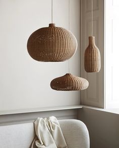 three wicker lamps hanging from the ceiling above a couch in a room with white walls