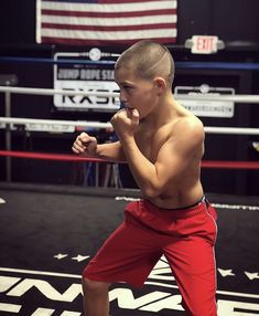 the young boy is practicing his moves in the boxing ring with an american flag behind him