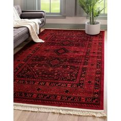 a large red rug with black and white designs on the floor in front of a window