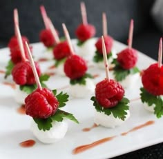 small appetizers with raspberries are arranged on a white plate