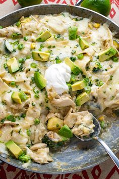 a skillet filled with chicken, avocado and sour cream sauce on top of a table