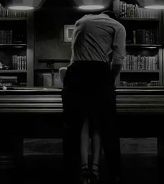 a man standing in front of a bookshelf filled with shelves full of books