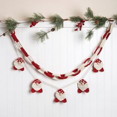 a christmas garland with red and white ornaments hanging from it's side on a wall