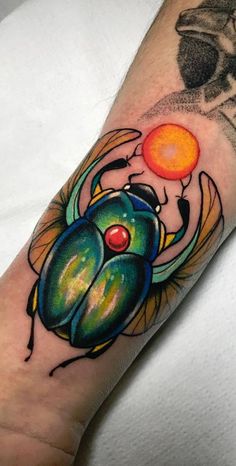 a colorful tattoo on the arm of a man with a scarroach and an orange ball