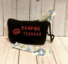 the vampire teabag has been embroidered onto it's black fabric with red lettering