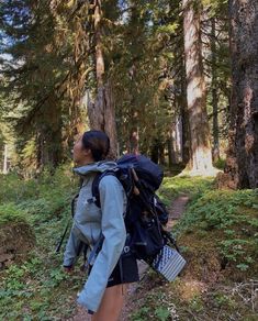 a woman with a backpack walking through the woods