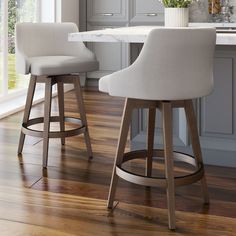 two white stools sitting in front of a kitchen counter with flowers on top of it