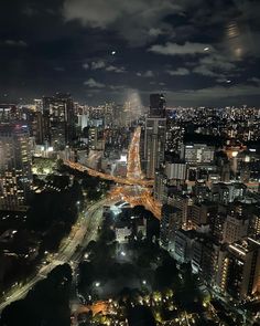 an aerial view of a city at night with lots of lights on the buildings and roads