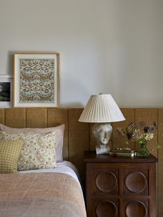 a bed room with a neatly made bed next to a night stand and a lamp