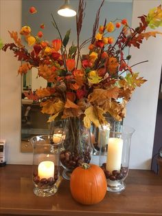 a vase filled with flowers and candles on top of a table next to a pumpkin