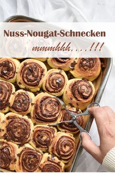 a person cutting into some cinnamon rolls in a pan with the words nuss - nougat - schnecken on it