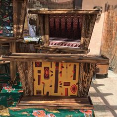 an old fashioned wooden box sitting on top of a green cloth covered table next to a building