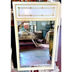 a large white mirror sitting on top of a table next to a vase and other items