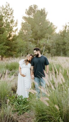 a man and woman standing in tall grass