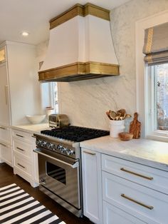 a stove top oven sitting inside of a kitchen next to white cabinets and counter tops