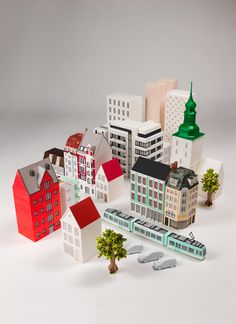 a group of paper houses with trees and buildings in the background