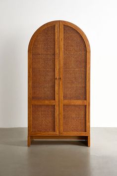 an arched wooden cabinet with wicker doors