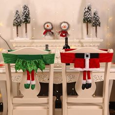 two santa clause christmas stockings sitting on top of chairs in front of a table with snowman decorations