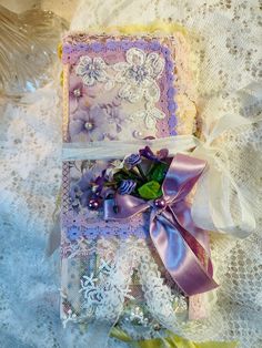 two small cards with ribbons on them sitting on a lace doily covered tablecloth