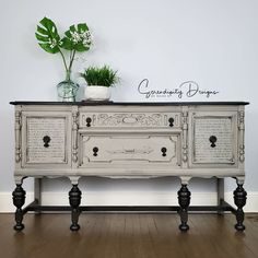 an old dresser is painted white with black trim and has a potted plant on top