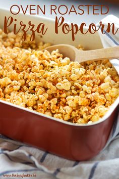 an oven baked pizza popcorn in a red casserole dish with a wooden spoon