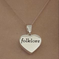 a silver necklace with a heart shaped pendant that says f folkloree on the front