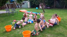 a group of young children playing in the yard with buckets and an umbrella over their heads