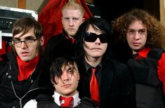 a group of young men in black and red outfits posing for a photo with sunglasses on