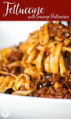 pasta with sausage and sauce in a white bowl on top of a red tablecloth