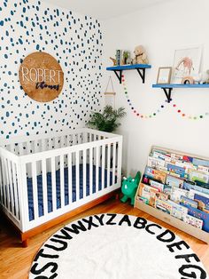 a baby's room with a white crib and blue polka dot wallpaper